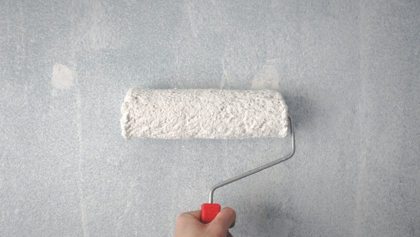 person holding paint roller on wall