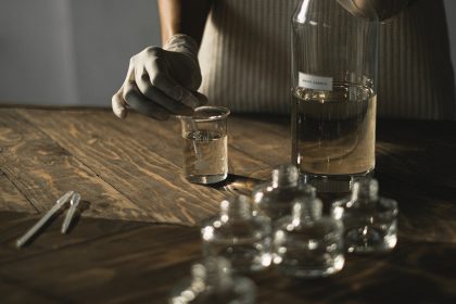 woman preparing aromatic perfume while mixing fluid in glassware
